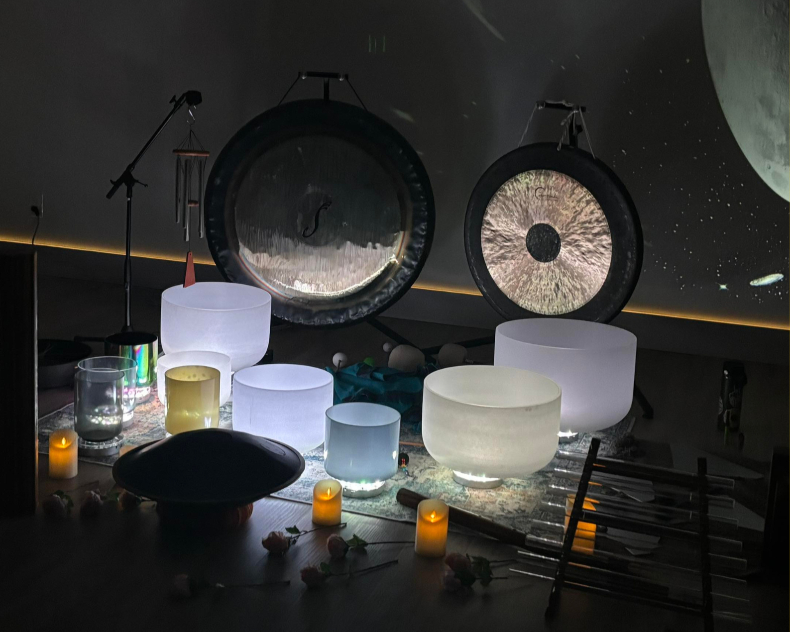 Gongs and glowing crystal bowls beneath a moon projection